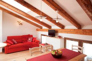 Albergo Diffuso Sauris in Sauris di Sotto في ساوريس: غرفة معيشة مع أريكة حمراء وطاولة