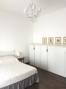 a white bedroom with a bed and a chandelier at La Casa di Anna in Siderno Marina