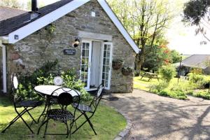 a table and chairs in front of a stone house at Almond Tree Cottage in Lanteglos