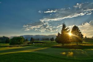 CarsonにあるCarson Hot Springs Resort & Spaの木々の後ろに沈む夕日を望むゴルフコースの景色