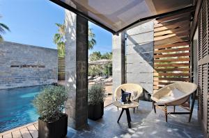 a patio with two chairs and a table next to a swimming pool at Hotel Boutique Ses Pitreras in San Antonio Bay