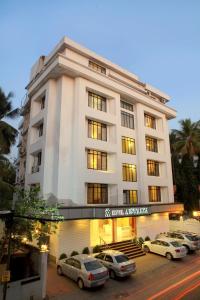 un edificio blanco con coches estacionados frente a él en Hotel Aiswarya, en Kochi