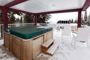 bañera de hidromasaje en una terraza con nieve en el suelo en Vacation Homes by The Bulldog- Henk's Haven, en Silver Star