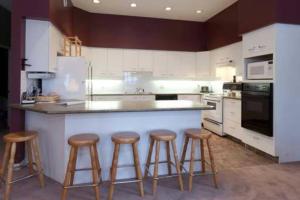 a kitchen with three bar stools and a large counter at Vacation Homes by The Bulldog- Henk's Haven in Silver Star