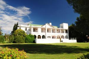 una gran casa blanca con un patio verde en Hostal de la Costa en Villa Carlos Paz