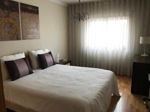a bedroom with a large white bed with a window at Varandas da Sandia in Vila Praia de Âncora