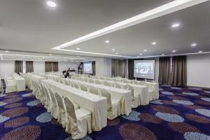 Sala de conferencias con sillas blancas y pantalla de proyección en Verdant Hill Hotel Kuala Lumpur, en Kuala Lumpur