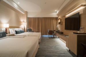 a hotel room with two beds and a flat screen tv at Fleur de Chine Hotel in Yuchi