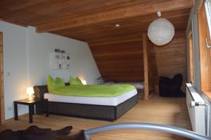 a bedroom with a bed with green sheets and wooden ceilings at Alpakatherapie und Ferienhof Charlottenthal in Charlottenthal +56 photos