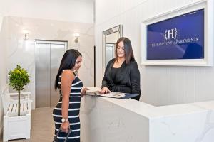 two women standing at a counter in a store at The Hamptons Apartments - Port Melbourne in Melbourne