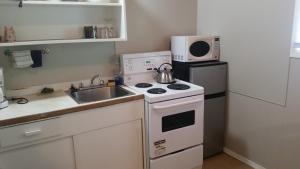 a kitchen with a stove and a sink and a microwave at Holiday House Motel in Penticton