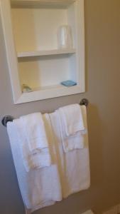 Un baño con toallas blancas colgando de un toallero. en Holiday House Motel, en Penticton