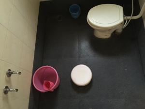 a bathroom with a toilet and a pink bucket at MTDC Approved Mohiniraj Guest House in Nashik