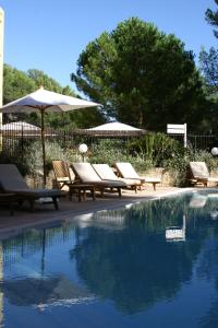 a swimming pool with lounge chairs and an umbrella at Hôtel Omega in Valbonne