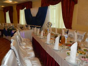 a dining room with white tables and white chairs at Yubileinaia in Sumy