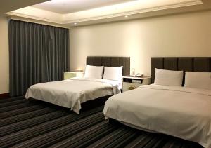 two beds in a hotel room with two beds sidx sidx sidx at Zaw Jung Business Hotel in Taichung