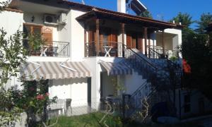 a white house with a balcony and stairs at Katerinas Apartments in Neos Marmaras