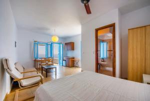 a white bedroom with a bed and a chair at Maki House in Anafi