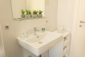 a white bathroom with a sink and a mirror at Hotel Delminivm in Zagreb