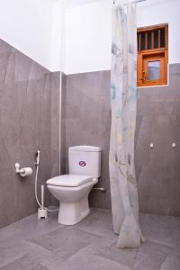 a bathroom with a toilet and a shower curtain at The Swiss Lankan in Ahangama