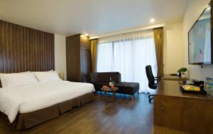 una camera d'albergo con letto, sedia e scrivania di Inearth Hotel a Hanoi