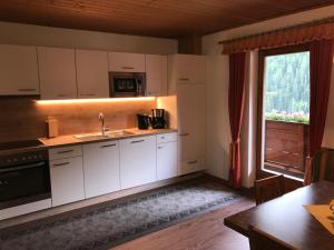 a kitchen with white cabinets and a large window at Haus Marita in Sankt Leonhard im Pitztal