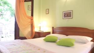 a bedroom with a bed with green pillows on it at Pefka Studios & Apartments in Vourvourou