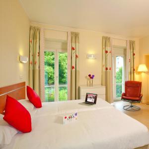 a bedroom with a large bed with a laptop on it at Hotels & Résidences - Les Thermes in Luxeuil-les-Bains