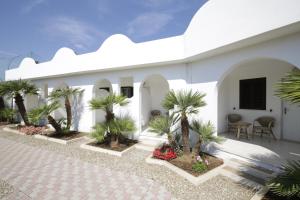 a white building with palm trees in the courtyard at Garden Hotel Ripa in Vieste
