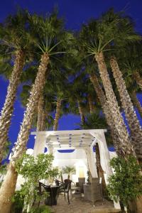 a patio with palm trees and tables and chairs at Garden Hotel Ripa in Vieste