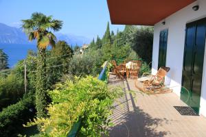 a balcony of a house with a palm tree and chairs at Villa Patrizia in Torri del Benaco