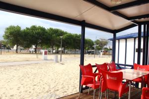 a table and red chairs in front of a beach at Torreira Camping & Bungalows in Torreira