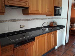 eine Küche mit Holzschränken und einem Waschbecken in der Unterkunft Apartments Aurora in La Robellada de Onis