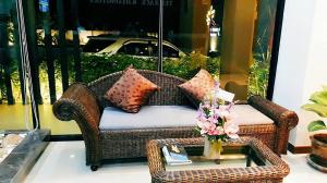 a wickericker chair with pillows and a table with a glass table at The Terrace Khlongtoei in Hat Yai
