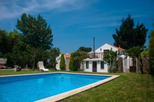 a villa with a swimming pool in front of a house at Casa Da Noquinhas in Bunheiro