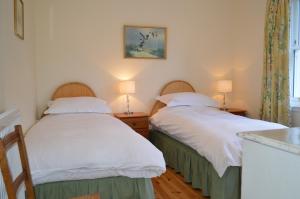 two twin beds in a room with two lamps at Shelduck Cottage in Feorlean