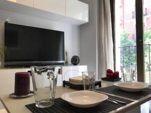 einen Tisch mit Tellern und Gläsern auf einem Tisch mit einem TV in der Unterkunft Moderno apart centro in Madrid