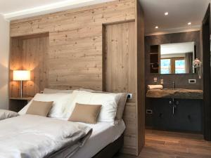 1 dormitorio con 1 cama blanca grande y pared de madera en Hotel Le Cime, en Val Masino