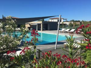 una piscina con sillas y flores frente a una casa en Résidence Pierre & Vacances Premium Les Villas de Porto-Vecchio, en Porto Vecchio