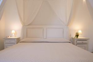 a bedroom with a white bed with two night stands at Antica Masseria Ficazzana - Tenuta in Marina di Pescoluse