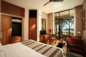 
a bedroom with a large bed and a large window at Heritance Kandalama in Sigiriya
