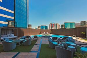 patio na dachu z krzesłami i basenem w budynku w obiekcie Somewhere Hotel Apartment w Dubaju