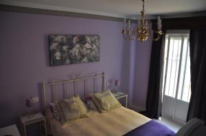 a bedroom with purple walls and a bed with pillows at Mirador de Santiago in Sanlúcar de Barrameda