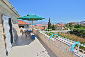einen Balkon mit einem Tisch und einem Sonnenschirm in der Unterkunft Villa CasaBlanca in Supetar