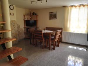 comedor con mesa, sillas y TV en Agávé Apartman, en Sárvár