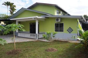 a green house with a tree in front of it at Budget Umi Homestay Kuching in Kuching