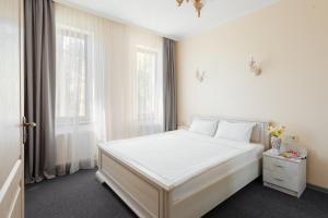 a white bedroom with a white bed and two windows at Asiya in Odesa