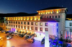 a large building with cars parked in a parking lot at Yantra Grand Hotel in Veliko Tŭrnovo
