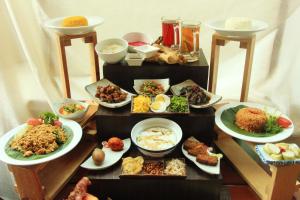 a table filled with different types of food on plates at Millennium Hotel Sirih Jakarta in Jakarta