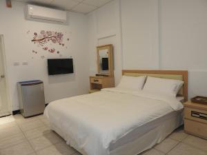 um quarto com uma cama branca e uma televisão em Mediterranean B&B em Fushan